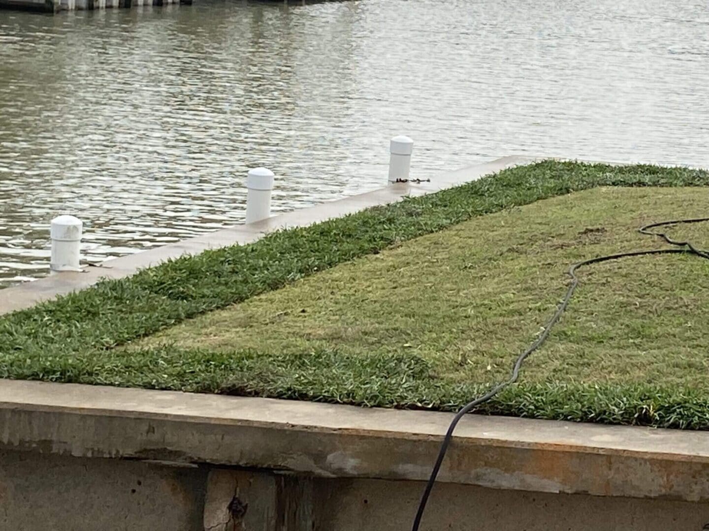 Grass area by water with white posts.
