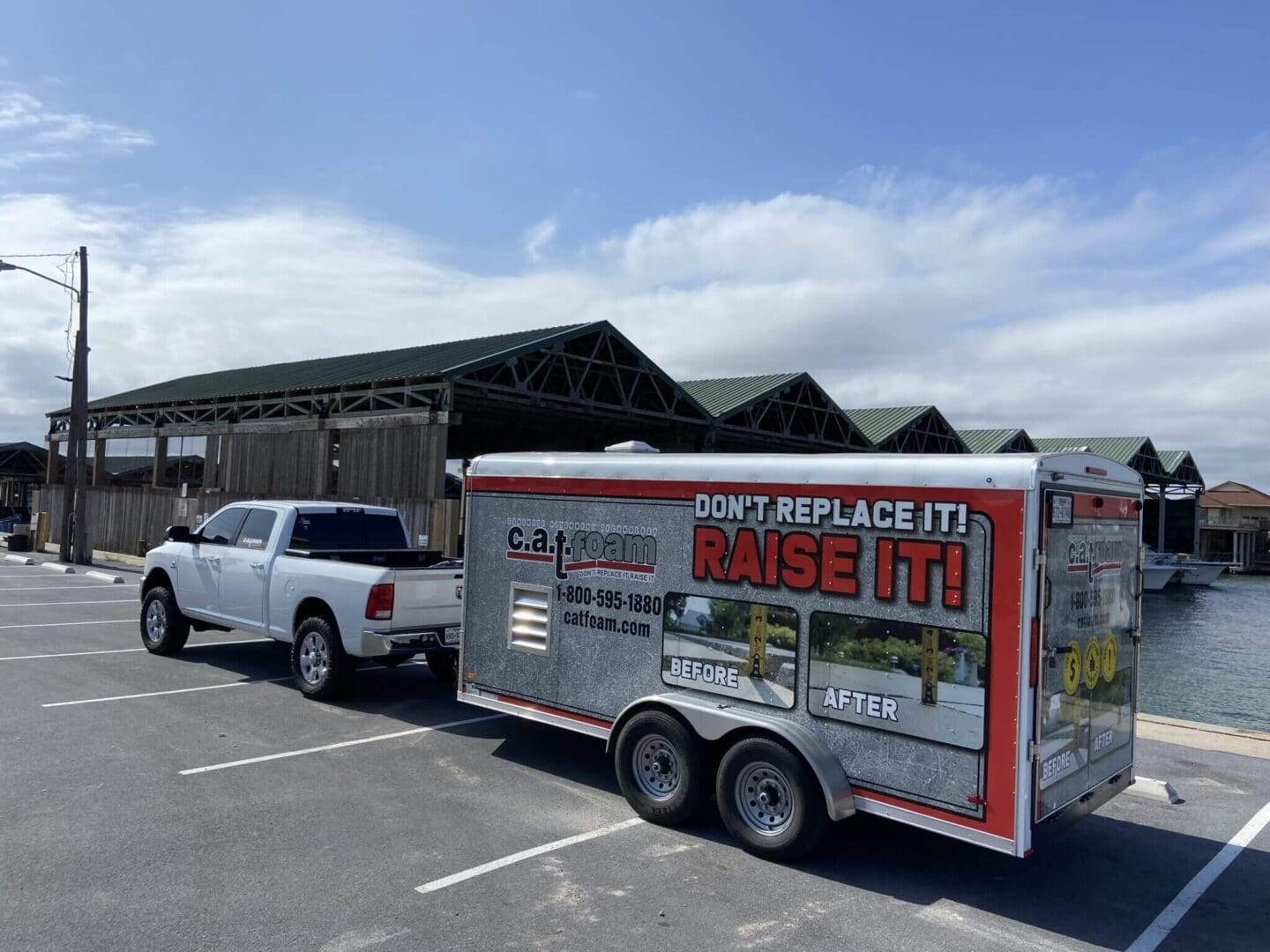 Truck towing trailer near waterfront buildings.
