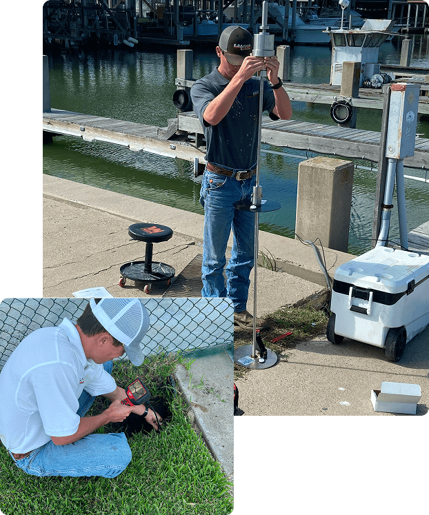 Two men working on technical equipment outdoors near water and greenery.