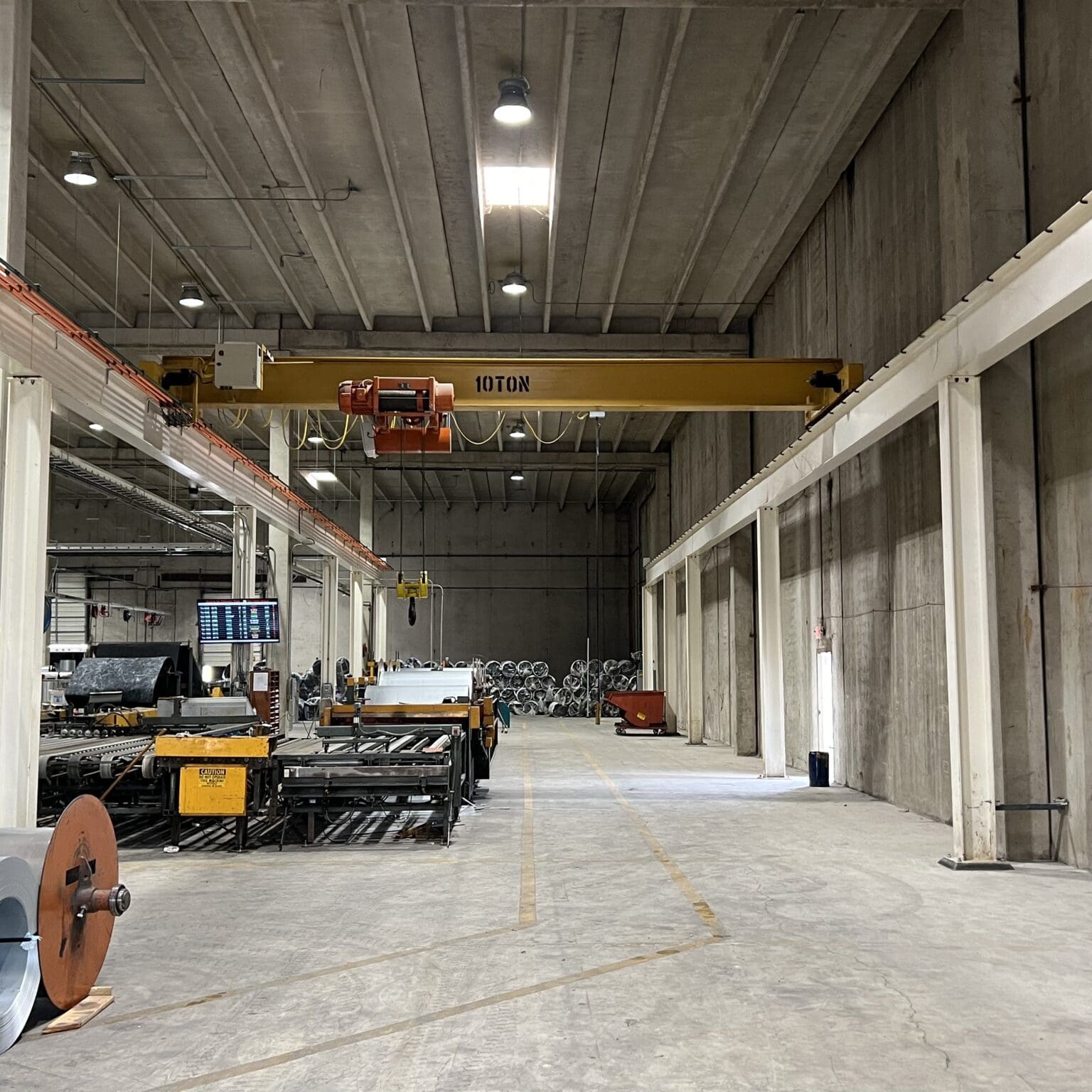 Industrial warehouse with machinery and overhead crane.